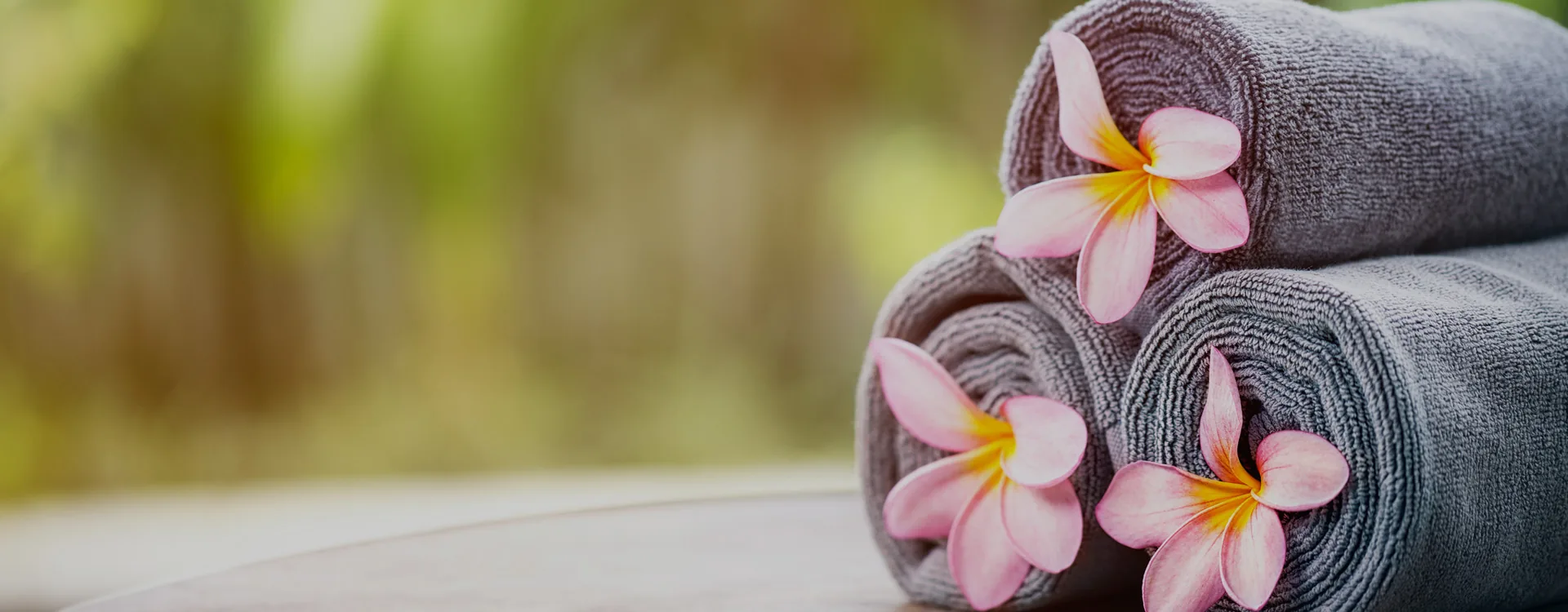 Orchideával díszített masszázskövek és törölközők